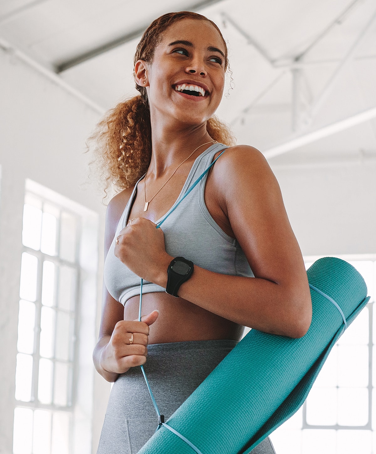 Smiling woman holding yoga mat in studio.