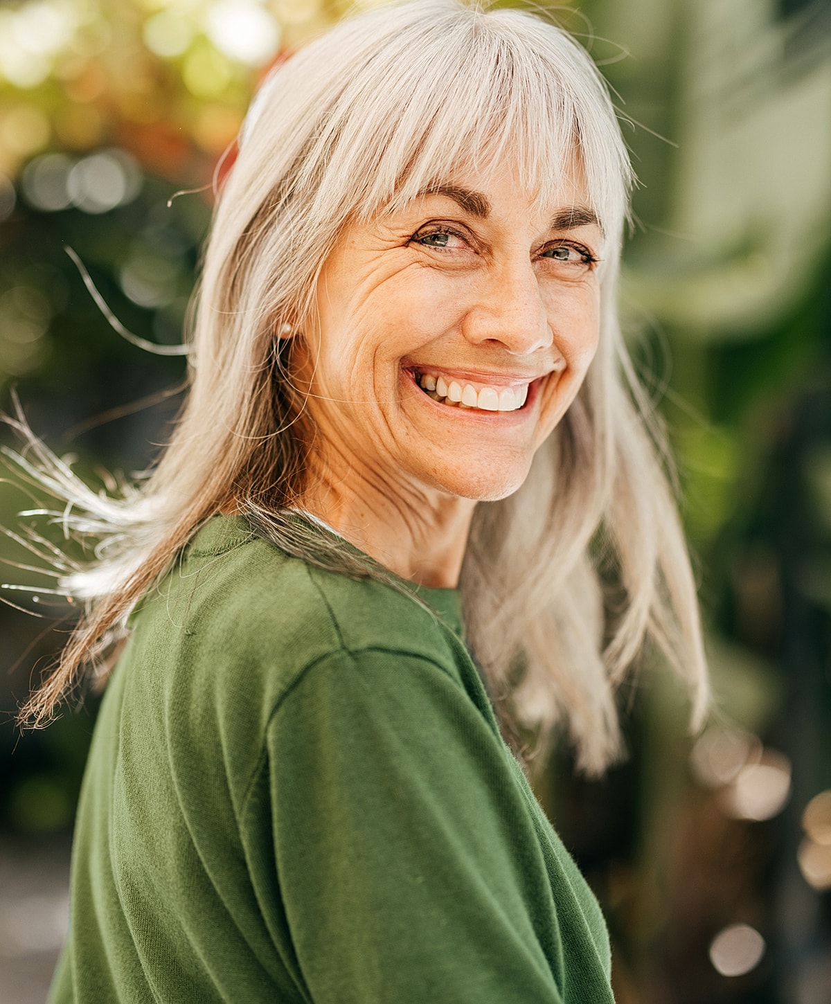 Smiling woman with gray hair outdoors.