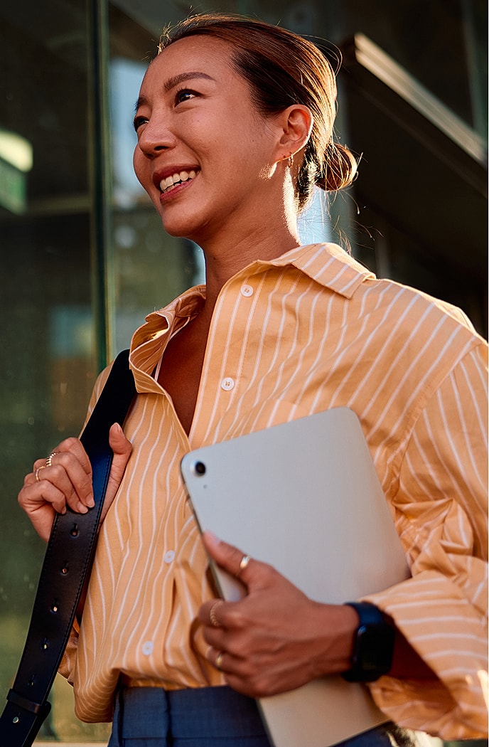 Smiling woman holding a tablet outdoors.