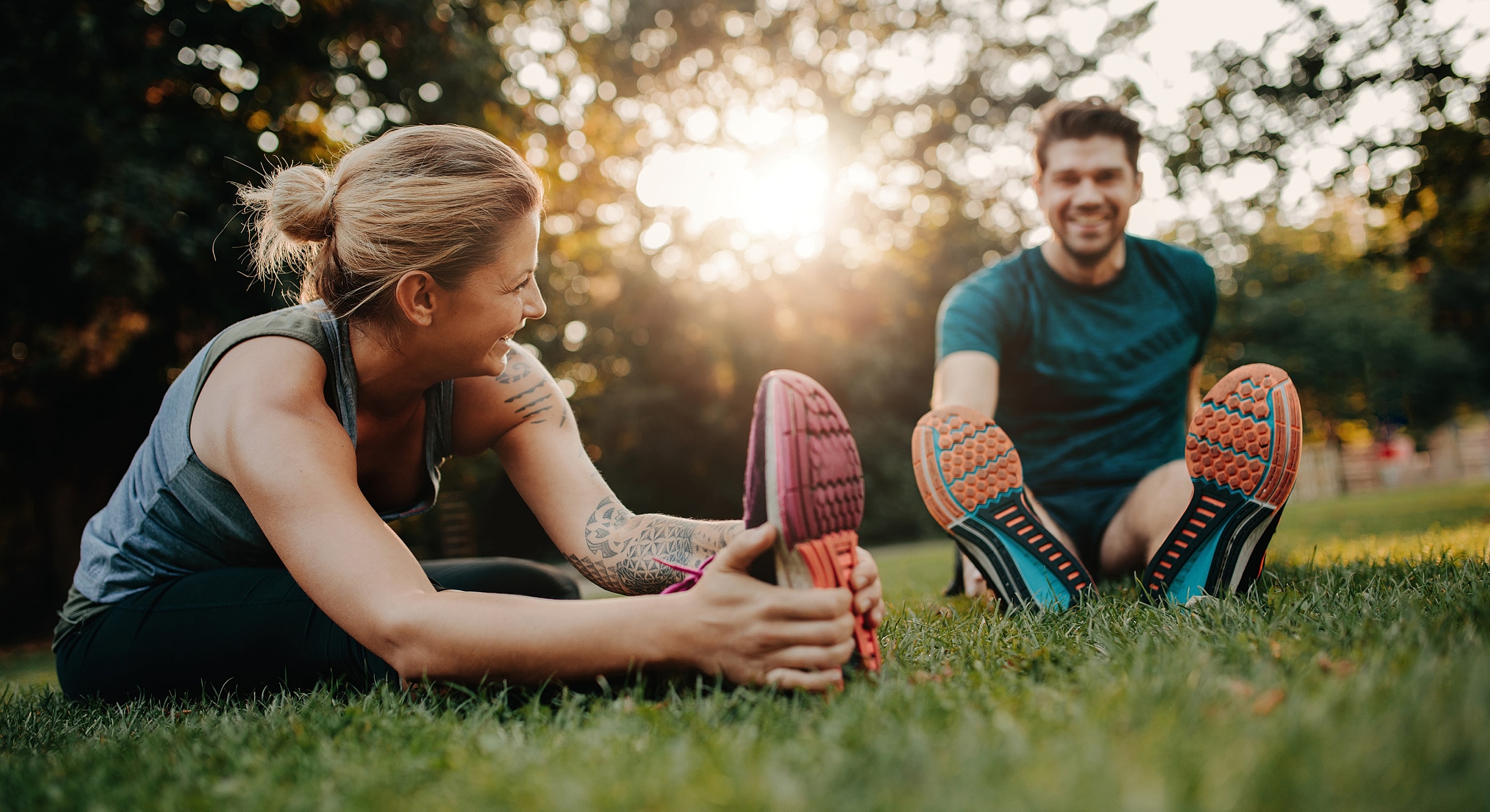 Couple stretching together outdoors in sunlight.