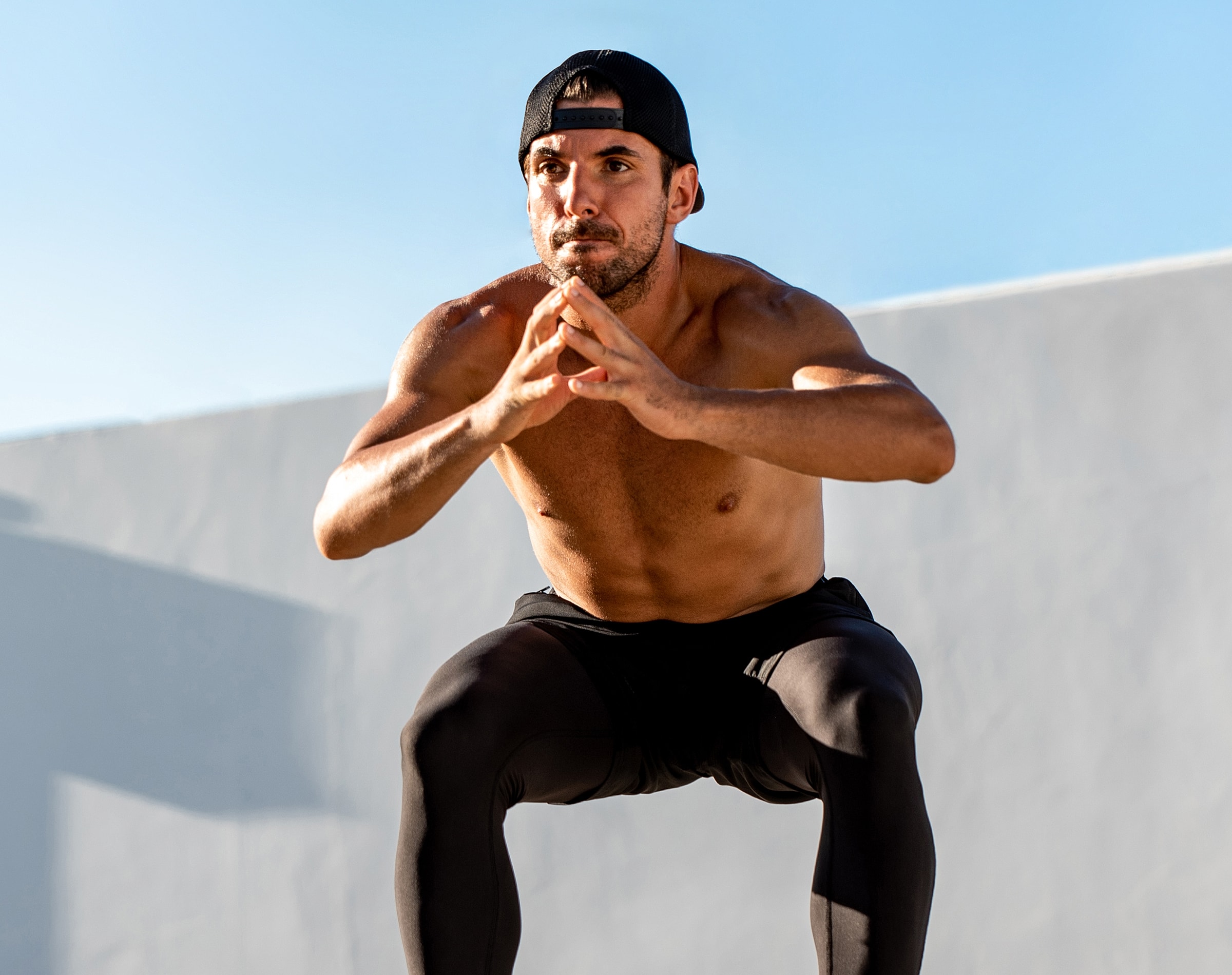 Man performing squats outdoors in athletic attire.
