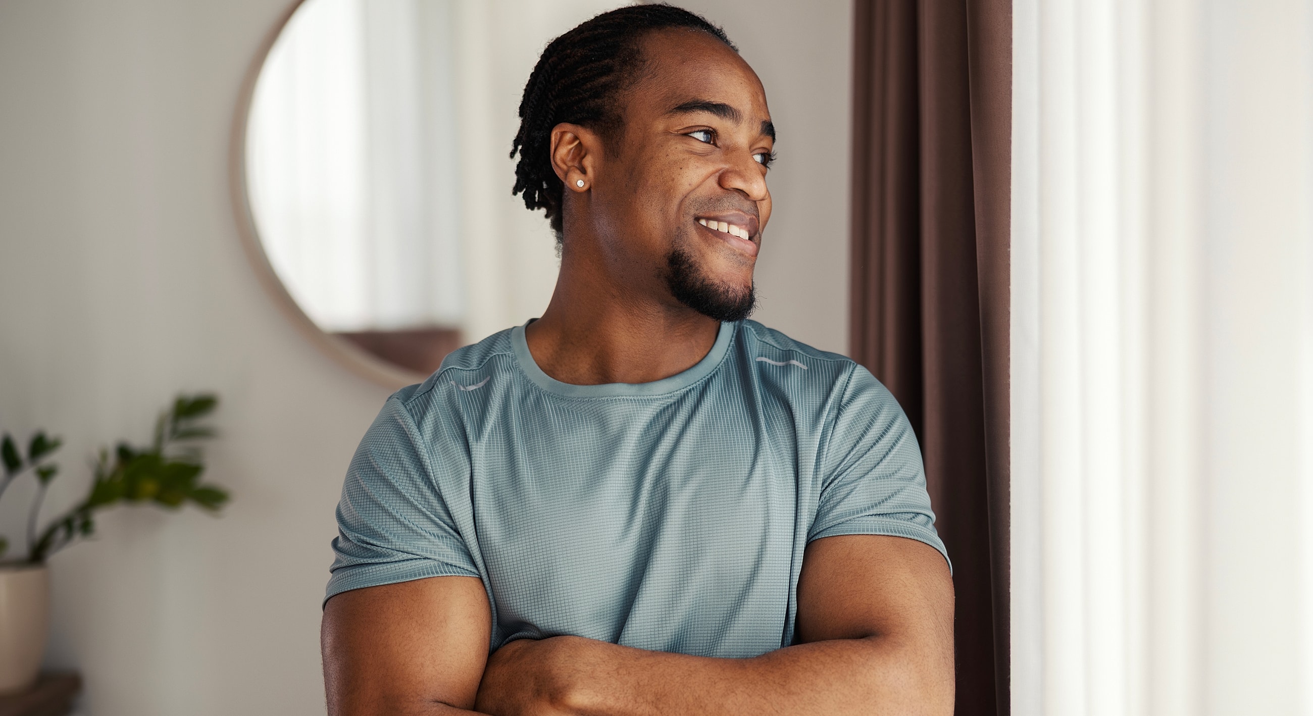 Smiling man in athletic wear by window.