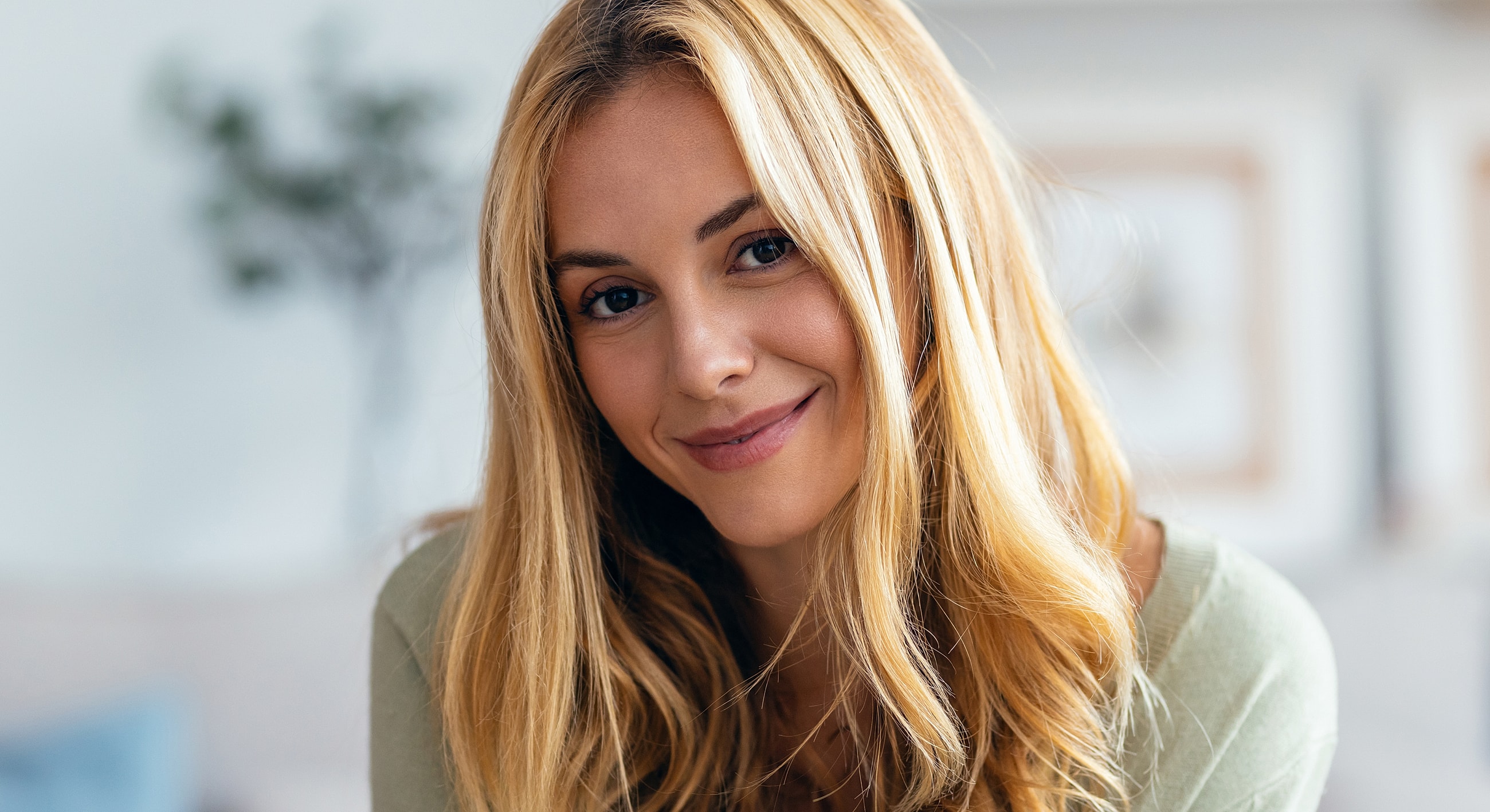 Smiling woman with long blonde hair indoors.